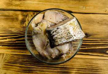 Pieces of the marinated carp in bowl on wooden table. Top view
