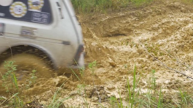 Car wheel on a dirt road. Off-road tire covered with mud, dirt terrain. Outdoor, adventures and travel suv. Car tire close-up in a countryside landscape with a muddy road. Four wheel truck in mud.