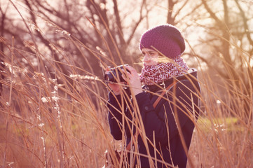 A beautiful shot of a woman with a camera in her hands. She takes a picture. The photo was taken on a spring evening. Tinted image.