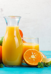 Citrus orange juices in jar and glass with oranges and mint