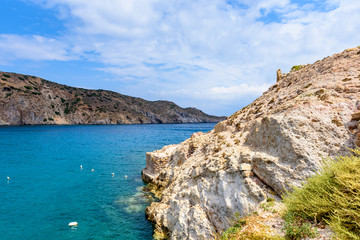 Fototapeta premium Rocks on the shore and azure sea water in Firopotamos Bay in sunny day. Milos, Cyclades Islands, Greece.