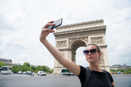 young woman making selfie in front of Triumphal arch