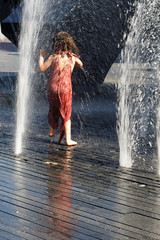 Child playing in a fountain with water 