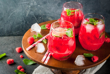 Summer refreshing non-alcoholic cocktails. Fruit drinks. Raspberry mojito lemonade with fresh organic mint and lime. On a black stone table. Copy space