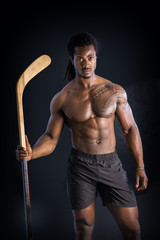 Fototapeta na wymiar Portrait of a handsome black man posing shirtless for camera with hockey stick in his hands