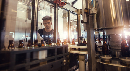 Obraz na płótnie Canvas Brewer supervising the beer bottling process