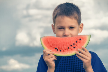 Child with watermelon against blue sky