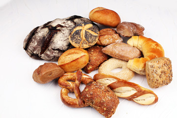 Different kinds of bread rolls on white board from above. Kitchen or bakery poster design.