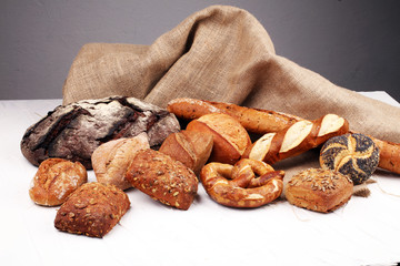 Different kinds of bread rolls on white board from above. Kitchen or bakery poster design.