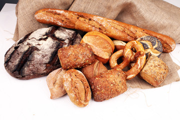 Different kinds of bread rolls on white board from above. Kitchen or bakery poster design.