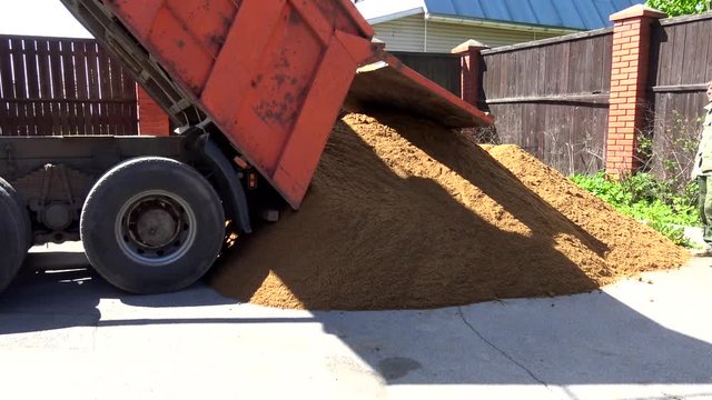 Dump truck unloads sand on the construction site. Trucks for transportation of bulk cargo.
