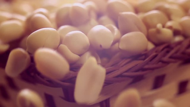 Purified peanuts are poured from a wicker basket with beautiful slow motion