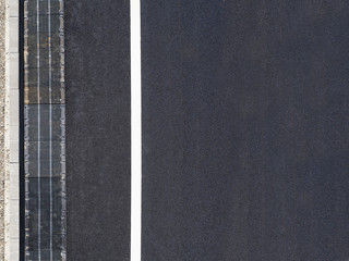 Highway background, roadside top view. Road view from above, black asphalt, white dividing strip, concrete curb, rainwater drainage system, runoff, rubble. - 161673730