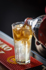 The barman pours cold drinks into a glass goblet