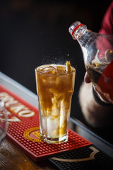 The barman pours cold drinks into a glass goblet