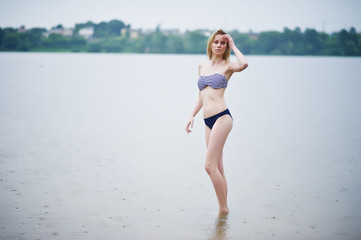 Portrait of a beautiful bikini model standing and posing in the water.