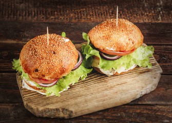 Delicious burgers on wooden cutting board. Top view