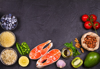 Selection of healthy and good for heart food. Healthy food concept with salmon, fresh vegetables, fruits and ingredients for cooking on dark background. Top view with copy space
