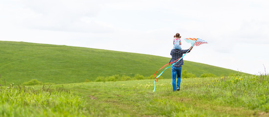 happy family father and baby daughter run with  kite on meadow.