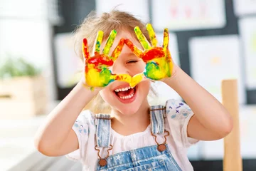 Fotobehang Kinderopvang grappig kind meisje tekent lachen toont handen vuil met verf