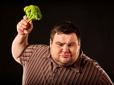 Diet fat man eating healthy food . Healthy breakfast with vegetables cauliflower . Male trying to lose weight. Concept on black background. Overweight person was on diet for long time.