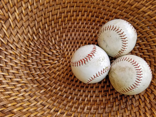 three baseballs in brown wicker basket