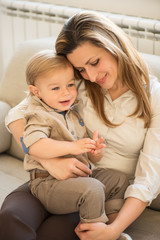 Portrait of beautiful mother and little son sitting in her lap. Family values.