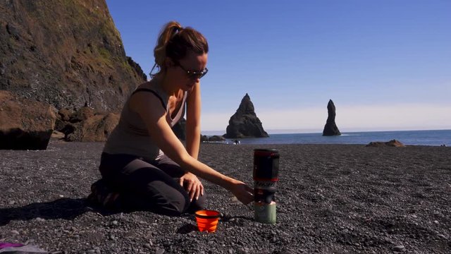 Woman making hot drink on Reynisfjara beach near Vik, Icealnd