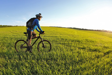 Fototapeta na wymiar cyclist rides a bicycle on the green field towards the sun