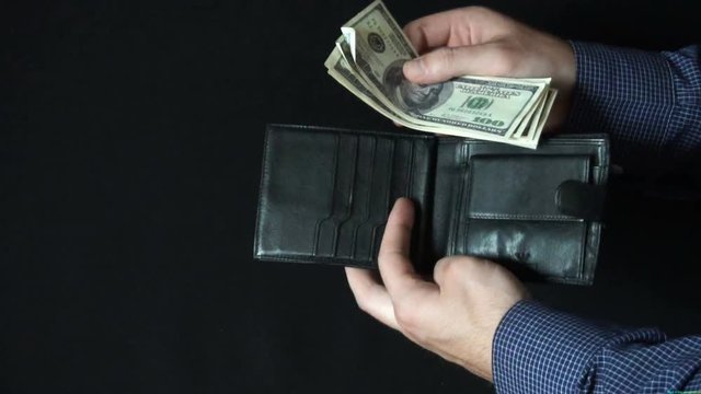 Taking Money Out of a wallet. The man opens a leather wallet and pulls out a 100 dollar bills. slow motion