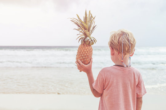 Caucasian boy from europe holding pineapple with happy and relax time on the tropical beach at Karon, Phuket province, Thailand