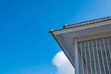 White eaves with ceiling and roof of modern house against blue sky.