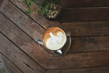 Top view of Hazelnut Latte Coffee with leaf frothy foam on wooden table