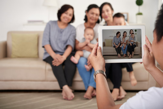 Portrait of big Asian family taking photo at home, all smiling happily on  tablet screen