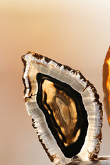 brown striped slice of agate stone on a light brown blurred background