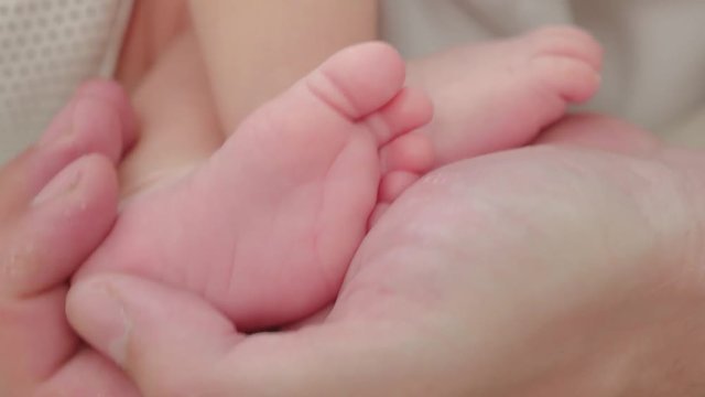 Baby legs in dad hands, closeup