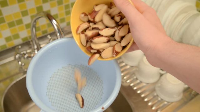 Wash the nuts in the colander in the kitchen.