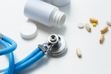  pills or capsules and stethoscope on the white table. Concept healthcare.