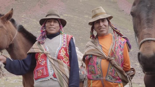 Couple of muleteers near horses on the highlands of Peru. Slow motion	