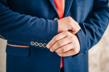 Closeup of a man in blue striped jacket correcting sleeves.