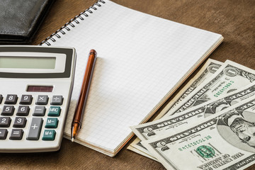 American dollars with calculator and notebook on the wooden table. Money counting.