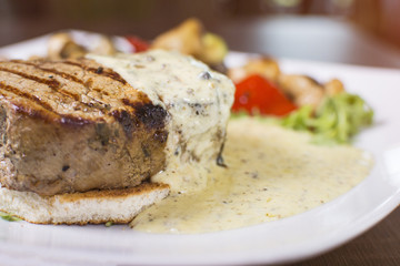 The steak set with the black pepper sauce and paprika and some vegetable. Close up of a beautifully served meal at the restaurant.