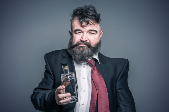 Wavy image of adult bearded man in suit holding in his hand a bottle of alcohol. Toned