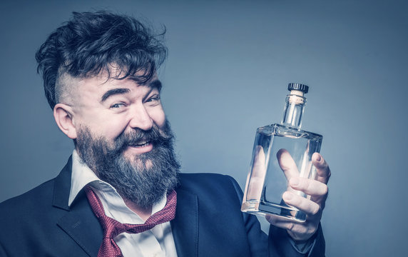 Cheerful drunk man with a beard holding a bottle of alcohol in his hand. Toned