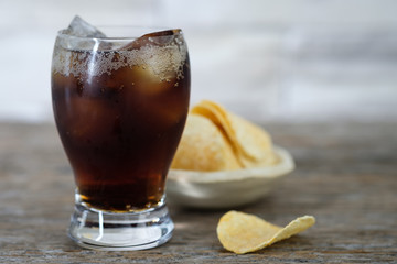 Glass of cold sparkling water and potato chips on wooden background, Choose focus point.