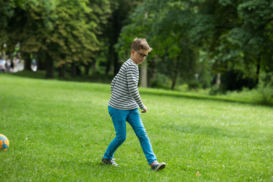 Jugendlicher / Heranwachsender / Junge / Kind spielt mit Fussball auf gr&uuml;ner Wiese / Wald