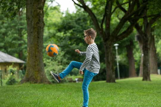 Jugendlicher / Heranwachsender / Junge / Kind spielt mit Fussball auf gr&uuml;ner Wiese / Wald
