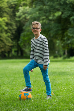 Jugendlicher / Heranwachsender / Junge / Kind spielt mit Fussball auf gr&uuml;ner Wiese / Wald