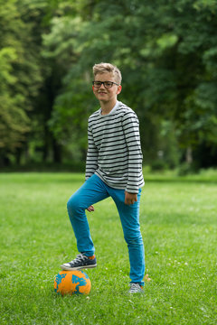 Jugendlicher / Heranwachsender / Junge / Kind spielt mit Fussball auf gr&uuml;ner Wiese / Wald