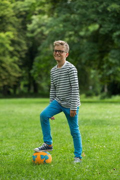 Jugendlicher / Heranwachsender / Junge / Kind spielt mit Fussball auf gr&uuml;ner Wiese / Wald